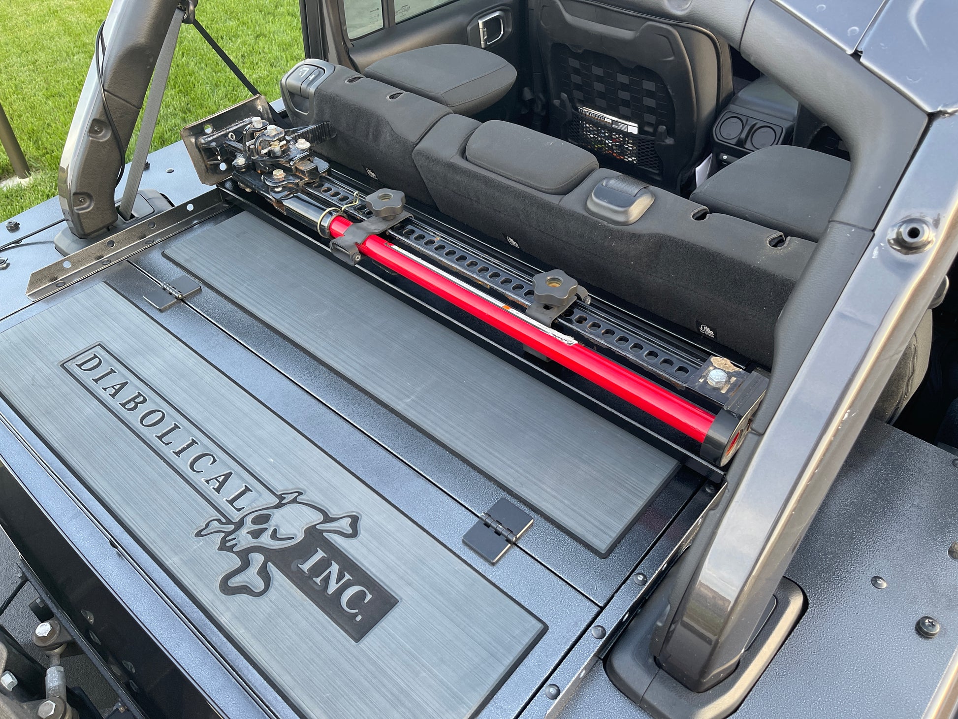 Image of a Jeep Wrangler JKU with a Diabolical, Inc. Slipstream security enclosure and foam deck pads with the Rail Rack accessory mount installed with a HiLift Jack.